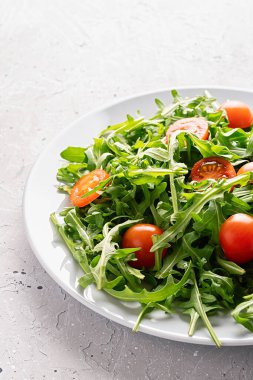 Taze salata, roka ve gri arka planda vişneli domates. Sağlıklı yiyecekler. Boşluğu kopyala