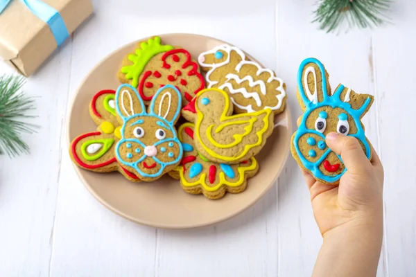 Das Kind hält einen Lebkuchen (Plätzchen) auf einem weißen Holzrücken — Stockfoto