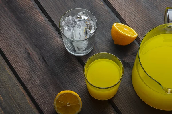 自制的新鲜柑橘类柠檬汁 放在水壶和玻璃杯中 玻璃杯中的木制背景是冰块 新鲜橙汁 有机饮料和新鲜维生素的概念 文本的复制空间 — 图库照片