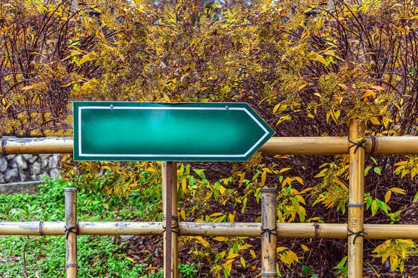 Direction sign mock up. Green arrow with empty blank with copy space for text among the autumn nature. Indicator the path in the forest, on hiking trails or in parks.