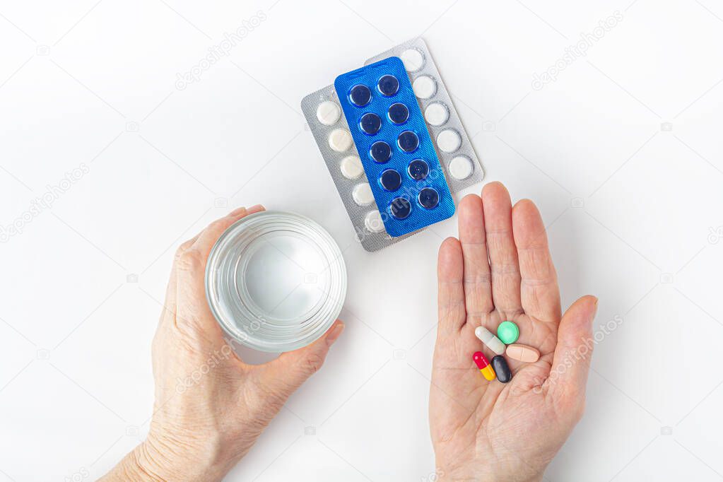 Female hand hold handful of different pills and glass of water. Healthcare and medical for elder. Medicines for treatment old senior people. Menopause or hormonal drug for woman. Copy space for text