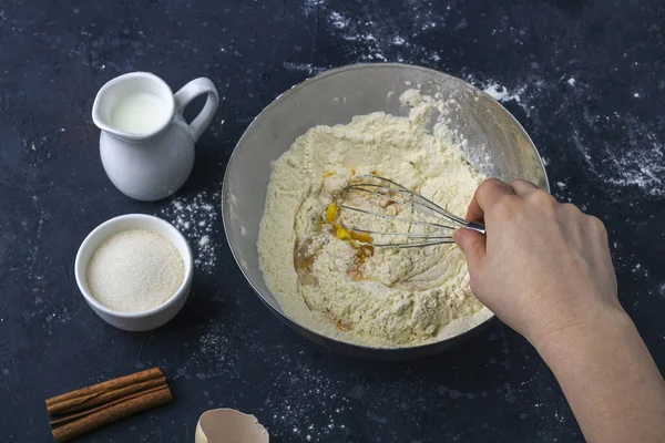 生地を準備し 小麦粉と卵を泡立てる女性の手 暗いテーブルの上でケーキ 小麦粉 圧延ピン タオル を調理するための成分と道具 ベーキング用生地を作るという概念 — ストック写真
