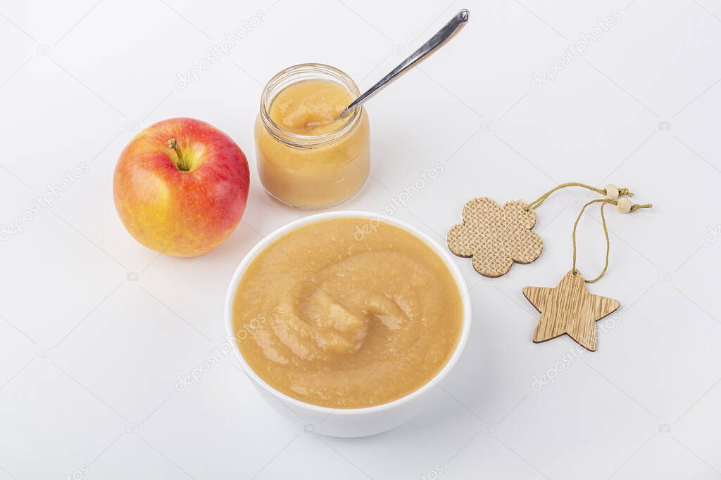 Fresh homemade applesauce in white bowl and jar with fruit puree on white table. The concept of proper nutrition and healthy eating. Organic and vegetarian food. Baby food. Close u