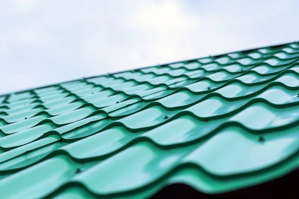 Tiled green roof against blue sky. Concept of building a new house or rooftops.