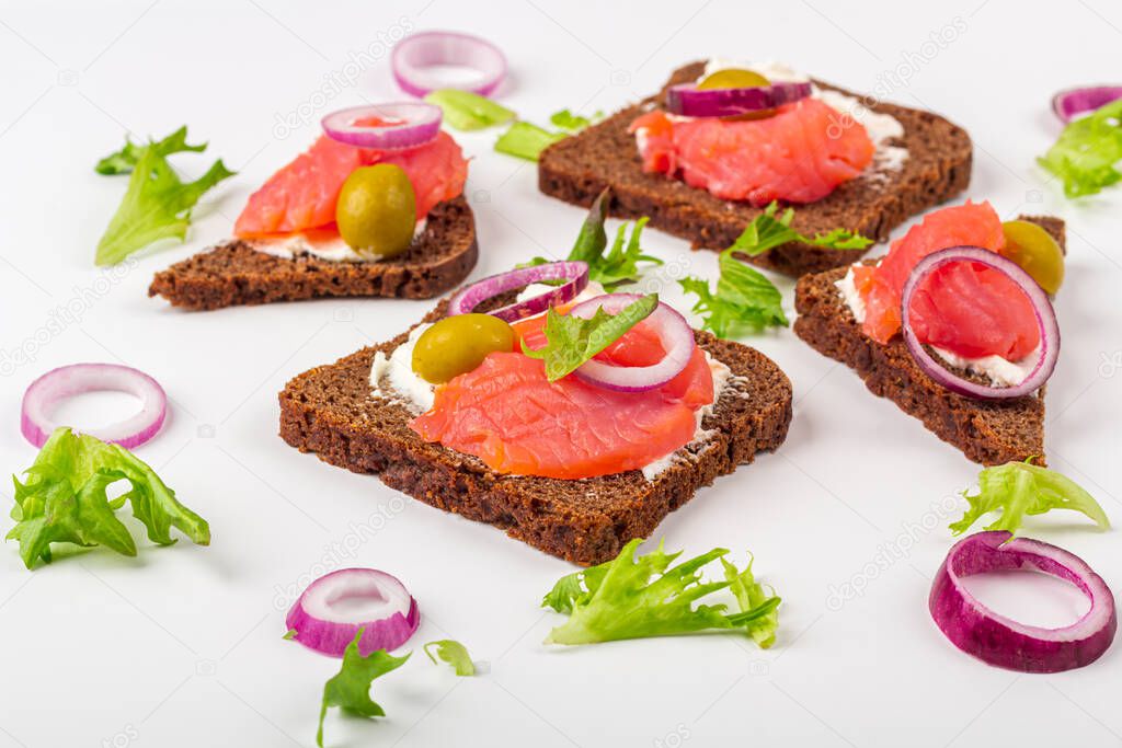 Appetizer, open sandwich with salmon and onion on white background. Traditional Italian or Scandinavian cuisine. Concept of proper nutrition and healthy eating. Close up