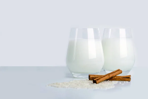 Two glass of vegatarian fermented rice drink Amazake. Non-alcoholic drink, cinnamon sticks and cereal rice on white background