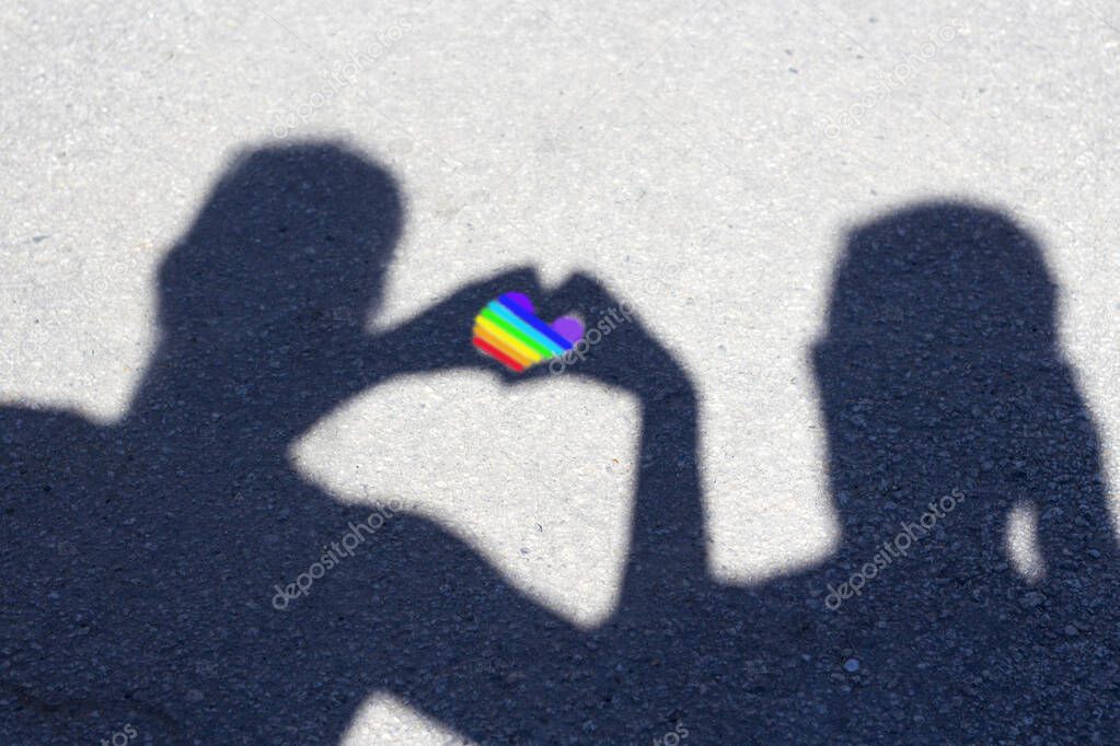 Silhouette of two guys with heart between them painted in LGBT colors. Concept of LGBT and human rights. Copy spase for text. Rainbow of hope