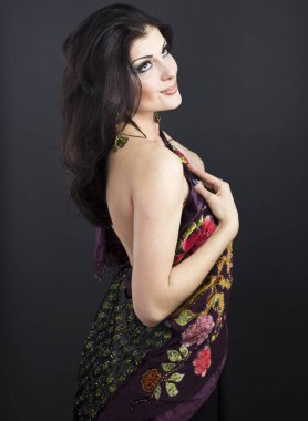 Güzel esmer işlemeli şal içinde. Siyah arka plan üzerine genç kadın portresi.