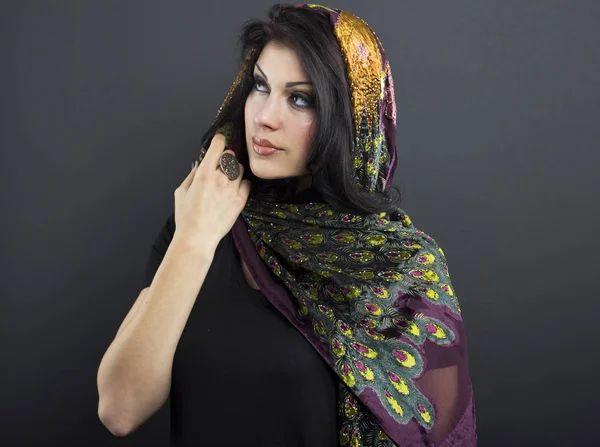 Beautiful brunette in embroidered shawls. Portrait of young woman on black background. — Stock Photo, Image