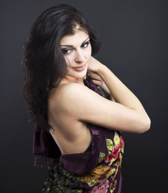 Güzel esmer işlemeli şal içinde. Siyah arka plan üzerine genç kadın portresi.