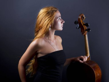 Karanlıkta bir çello ile güzel kız. Violonchello. Uzun düz saçlı kız