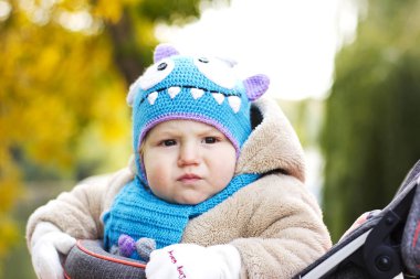 Komik bir şapka evlat. Çocuk temiz havada yürür. Çocuk sarı yapraklarda oynuyor