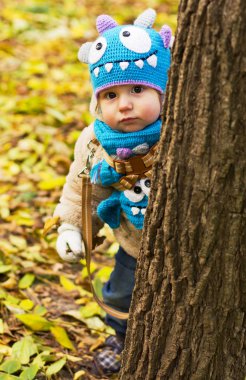 Komik bir şapka evlat. Çocuk temiz havada yürür. Çocuk sarı yapraklarda oynuyor