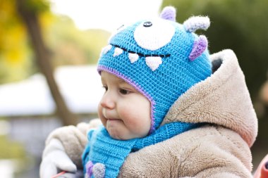 Komik bir şapka evlat. Çocuk temiz havada yürür. Çocuk sarı yapraklarda oynuyor