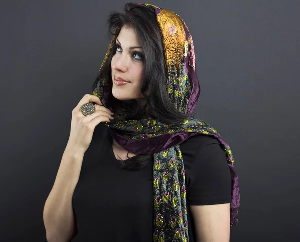 Güzel esmer işlemeli şal içinde. Siyah arka plan üzerine genç kadın portresi.