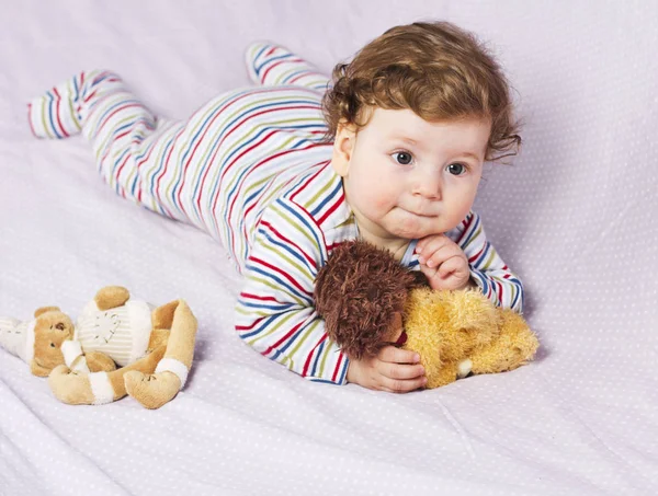 Il ragazzino nella culla con i giocattoli. Il bambino in casa — Foto Stock