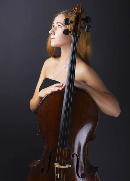 Belle fille avec un violoncelle dans le noir. Violonchello. Fille aux cheveux longs et raides — Photo