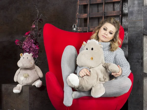 Sorrindo Menina Sentada Com Brinquedos Suaves Uma Cadeira Vermelha — Fotografia de Stock