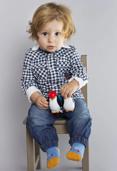 Gri bir arka plan üzerinde elinde dürbün çocukla çocuk. Oynayan çocuk. Bir çocuk oyuncakları ile. — Stok fotoğraf
