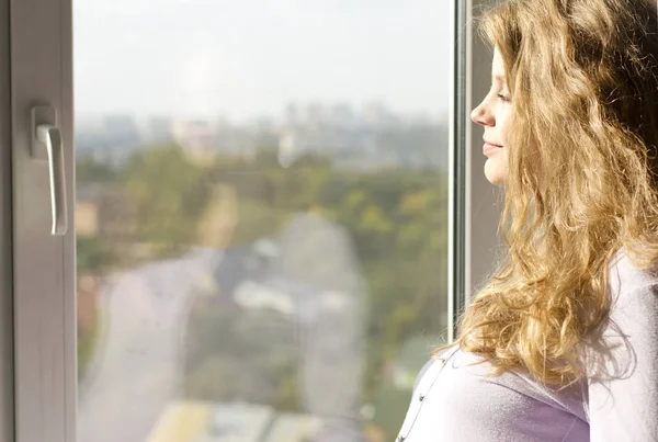 Vackra gravid blondin stående nära fönstret och njuta av solen — Stock fotografie