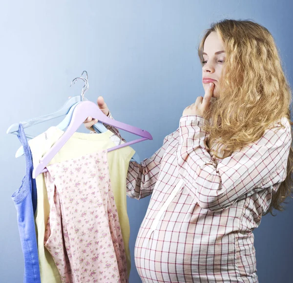 Hermosa rubia embarazada elige ropa. Retrato de la mujer embarazada . — Foto de Stock