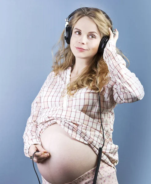 A mulher grávida ouve música. Mulher em fones de ouvido — Fotografia de Stock