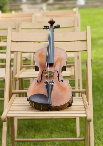 Violin on a wooden chair. Live music at the wedding.