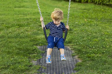 Çocuk salıncakta sallanıyor. Çocuk dışarıda oynuyor.