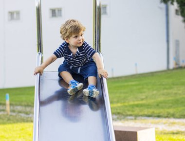 Çocuk demir bir kaydırağa biniyor..