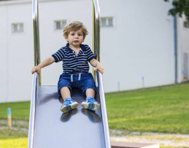 Çocuk demir bir kaydırağa biniyor..