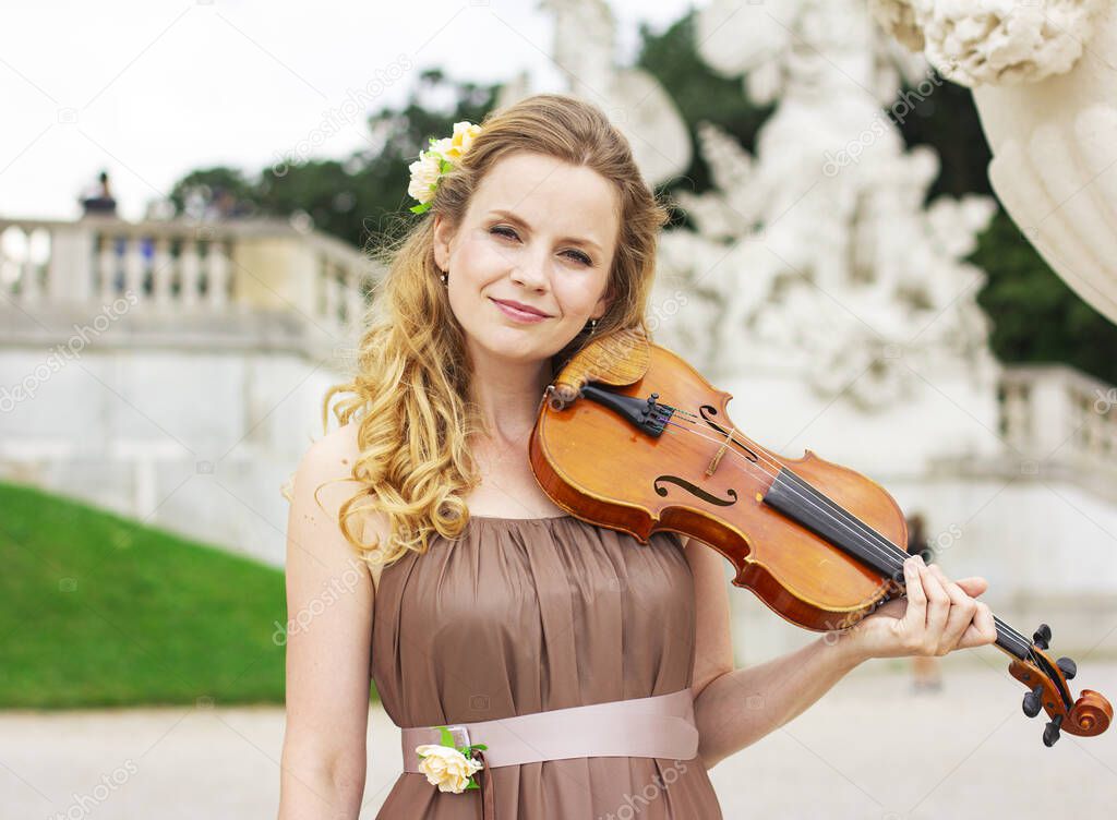 Beautiful blonde woman plays the violin outdoors. Violinist outdoors. 