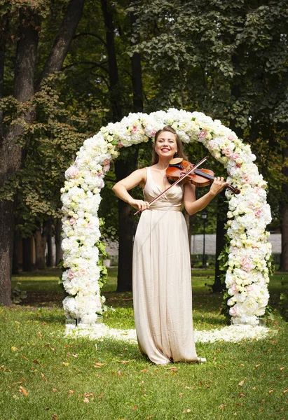 Beautiful young girl plays the violin. Girl with long hair plays the violin.Bride plays the violin.