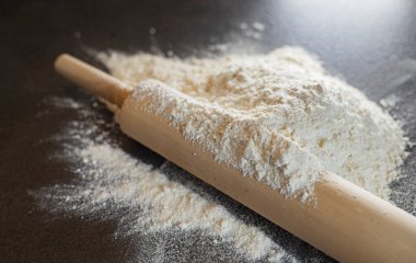 Siyah masaya yuvarlanan iğne ve un. Siyah arkaplanda buğday unu.