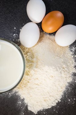 Geçmişi. Siyah arka planda yemek pişirmek için gerekli malzemeler. Hamur için gerekli malzemeler. Yumurta, süt, un..