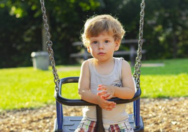 Çocuk bahçede salıncakta sallanıyor. Küçük çocuk yürüyüşe çıktı..