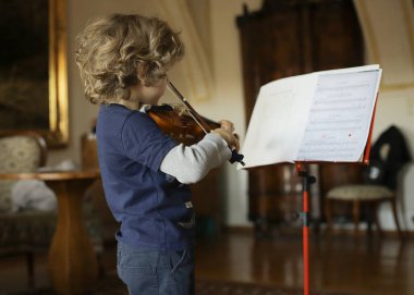 Evde küçük bir çocuk keman çalar. Çocuk müzik öğreniyor..