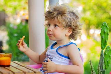 Çocuk dışarıda yemek yiyor. Küçük çocuk kahvaltı yapıyor.. 