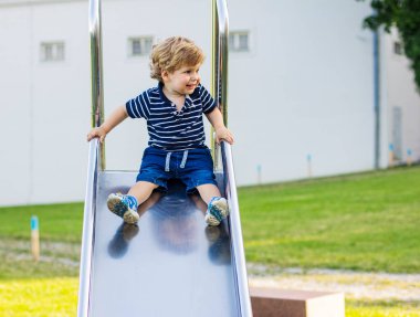 Çocuk tepeden aşağı yuvarlanıyor. Küçük çocuk salıncakta.