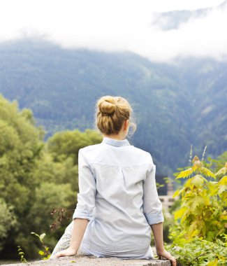 Dağlarda meditasyon yapan bir kadın. Genç bir sarışın dışarıda oturuyor..