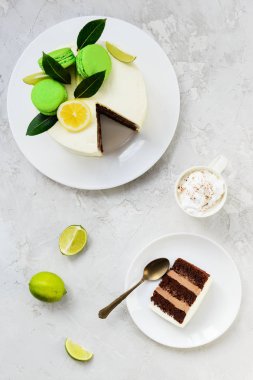 Bir dilim çikolatalı kek ve gri bir masanın üzerinde bir fincan kahve. Dikey yönelim, üst görünüm.