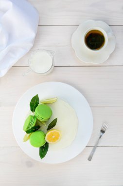 Krem peynirli ev yapımı kek. Makaronlarla süslenmiş. Beyaz ahşap bir masada taze limon ve limon. Dikey yönelim, düz yatış.