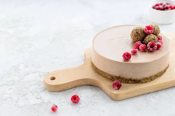 Enerji topları ve ahududularla süslenmiş çiğ kakaolu kek. Glütensiz. Yatay yönelim, boşluğu kopyala.