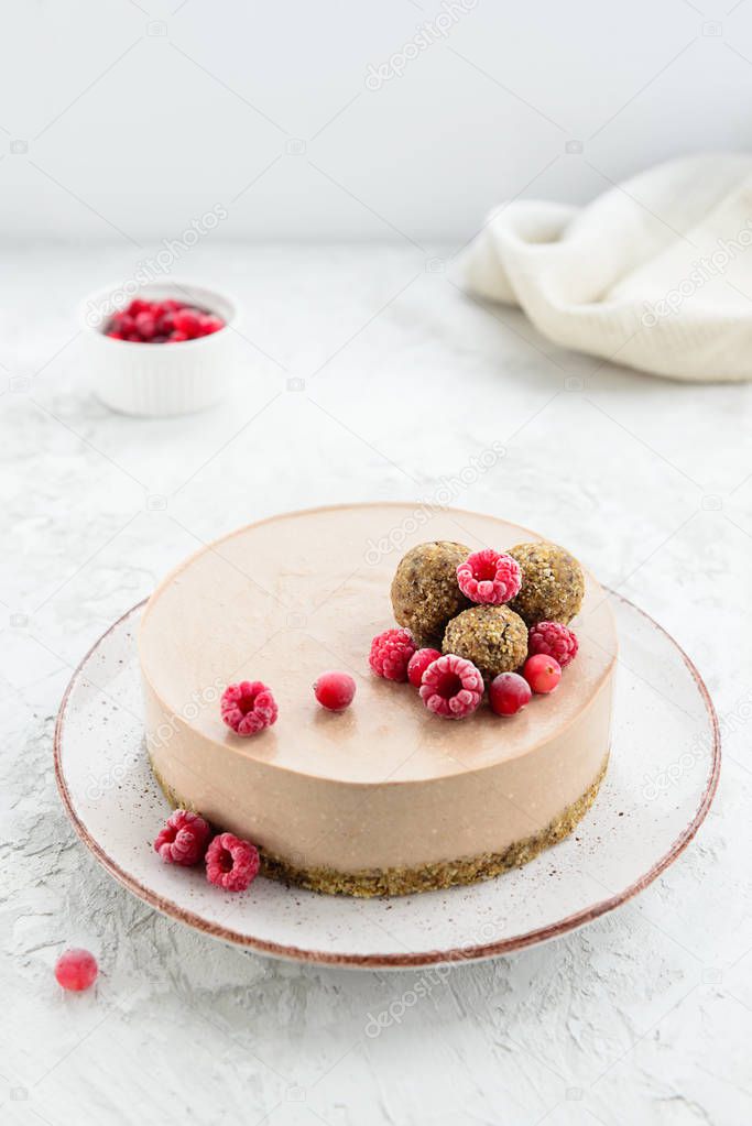 Raw cocoa cake garnished with energy balls and raspberries. Gluten free.