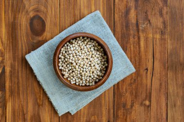 Kahverengi ahşap bir masada bir kasede nohut..