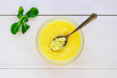 Tahta masadaki bitkilerle dolu bir kasede tereyağı..