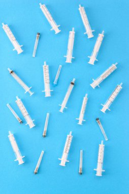 Mavi arka planda iğneleri olan tıbbi şırıngalar. Dikey yönelim, üst görünüm.