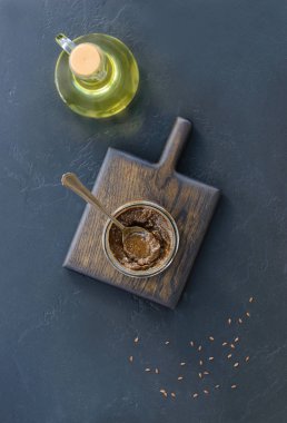 Koyu arkaplandaki yağ kavanozuna keten yapıştırıcı. Dikey yönelim, üst görünüm.