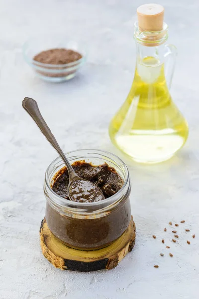 Kavanozda keten macunu ve gri bir masada yağ..