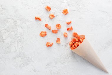 Gri bir arka planda kağıt torbada havuç cipsi..