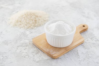 Tahtadaki beyaz bir kasede pirinç unu. Glütensiz, sağlıklı beslenme konsepti.